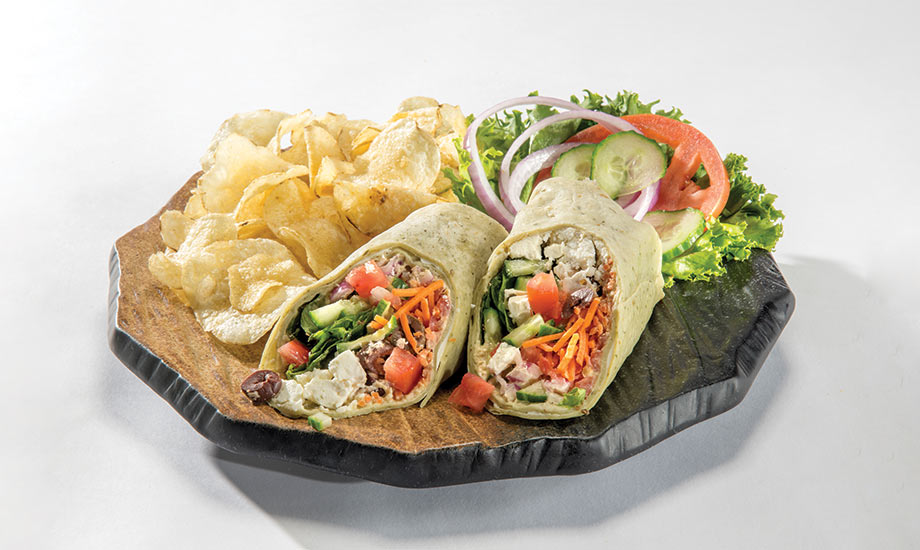 Image of Greek vegetarian wrap served with potato chips, and lettuce, tomato, onion and pickle