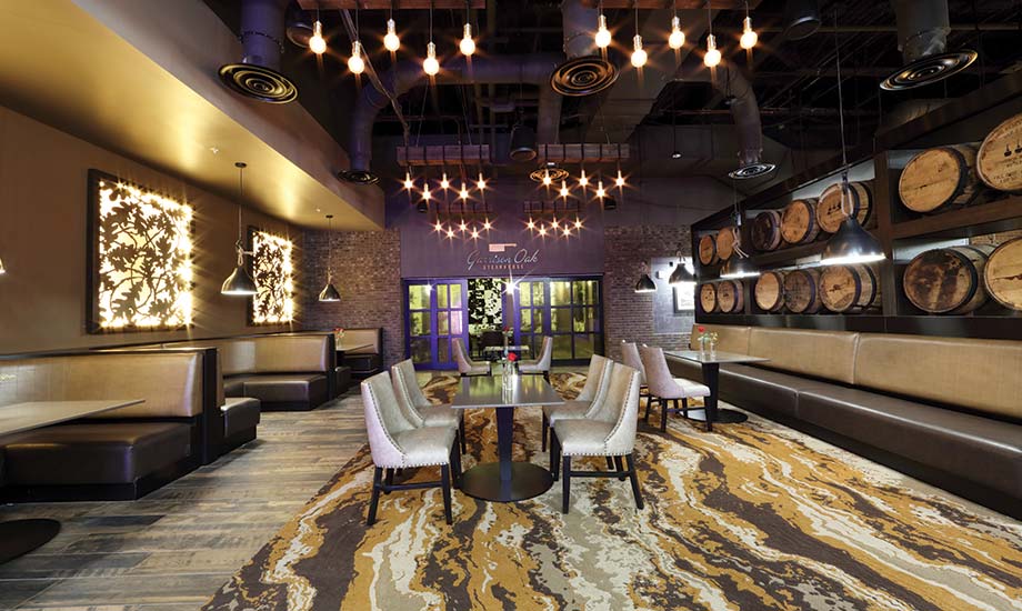 Image of the Garrison Oak Steakhouse dining area shows booths and tables and the wall of oak barrels