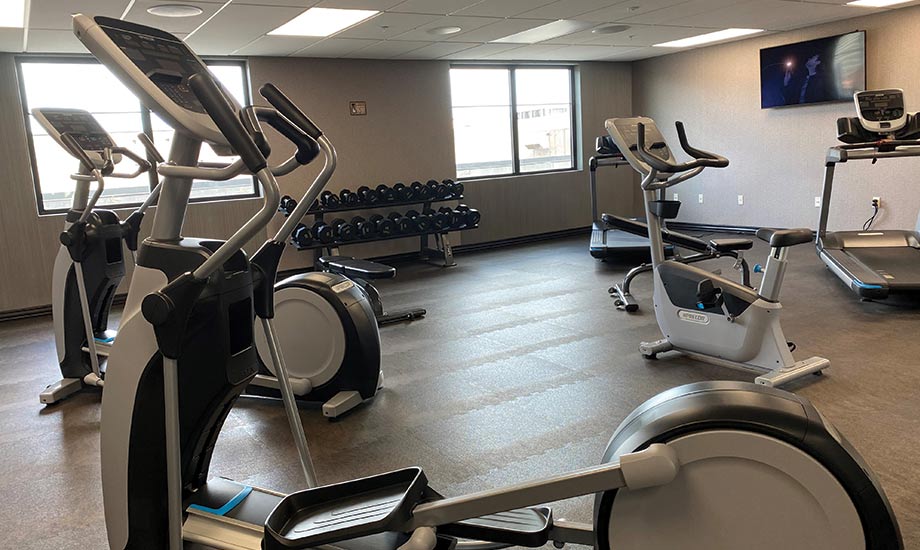 Image shows the fitness center at Oak Grove Racing, Gaming and Hotel complete with multiple cardio machines, a weight bench and dumbbells