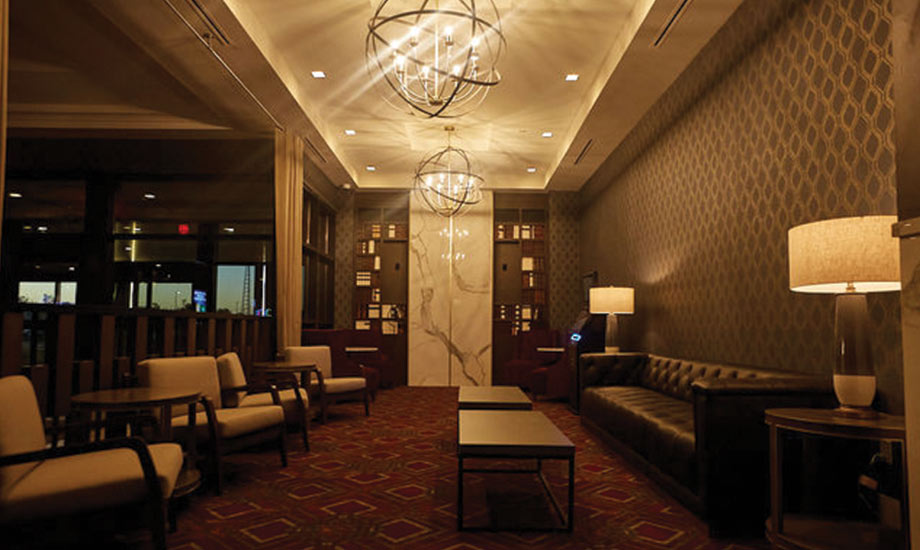 Image shows a seating area in the hotel lobby with bookshelves, chairs, couch and coffee tables