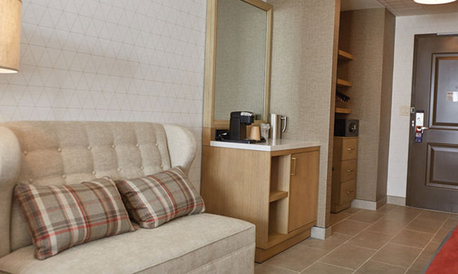 Image shows couch, coffee bar, closet area and door of the hotel room