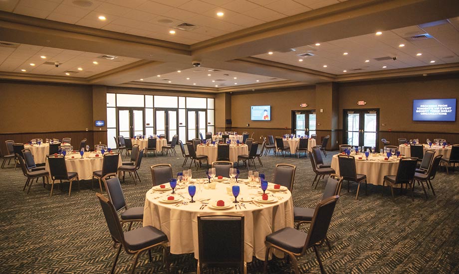 Image of the PreFunction event space set up for an event with multiple circle tables/chairs and places set for dining.