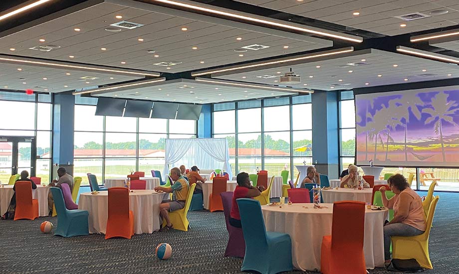 Image shows guests seated in Grandstand event area overlooking the track. The event space is filled with circle tables, colorful chairs, and beach balls.