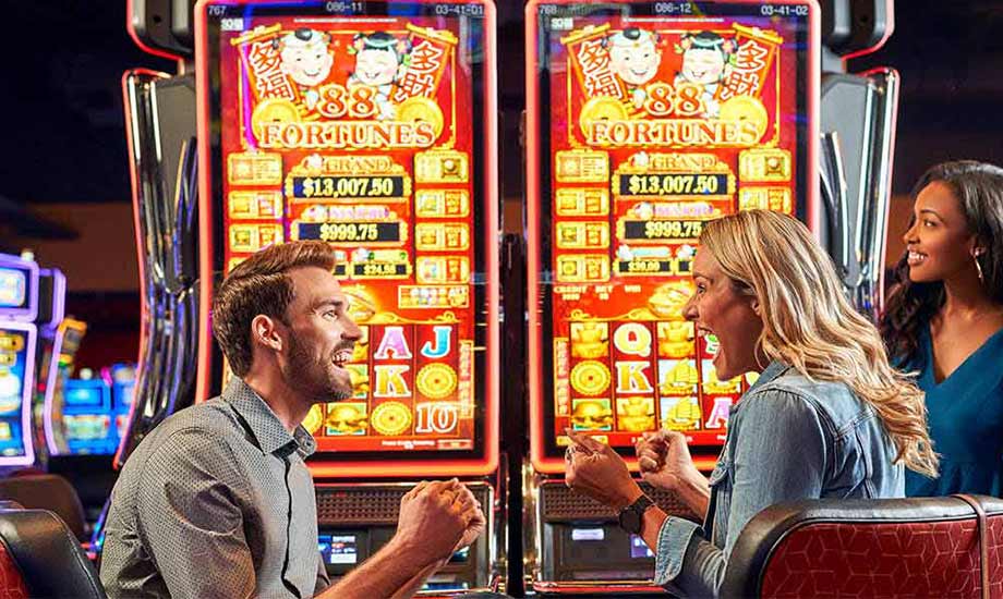 Image shows a man and woman celebrating in front of 88 Fortunes game machines while another woman looks on