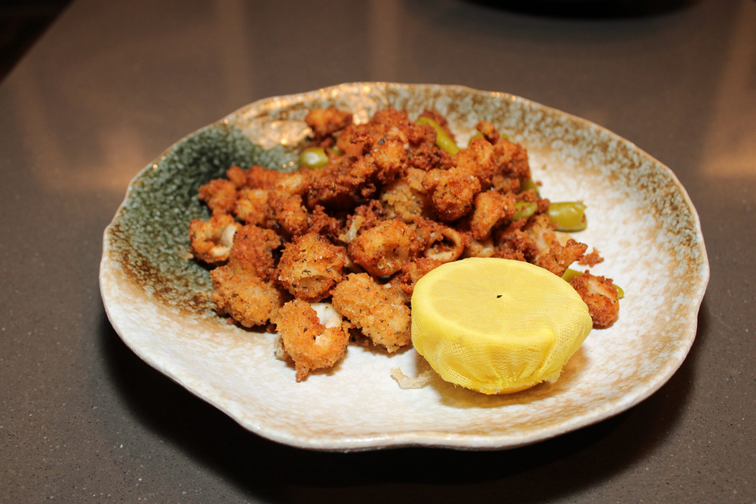 Image shows a plate of fried calamari with half a lemon
