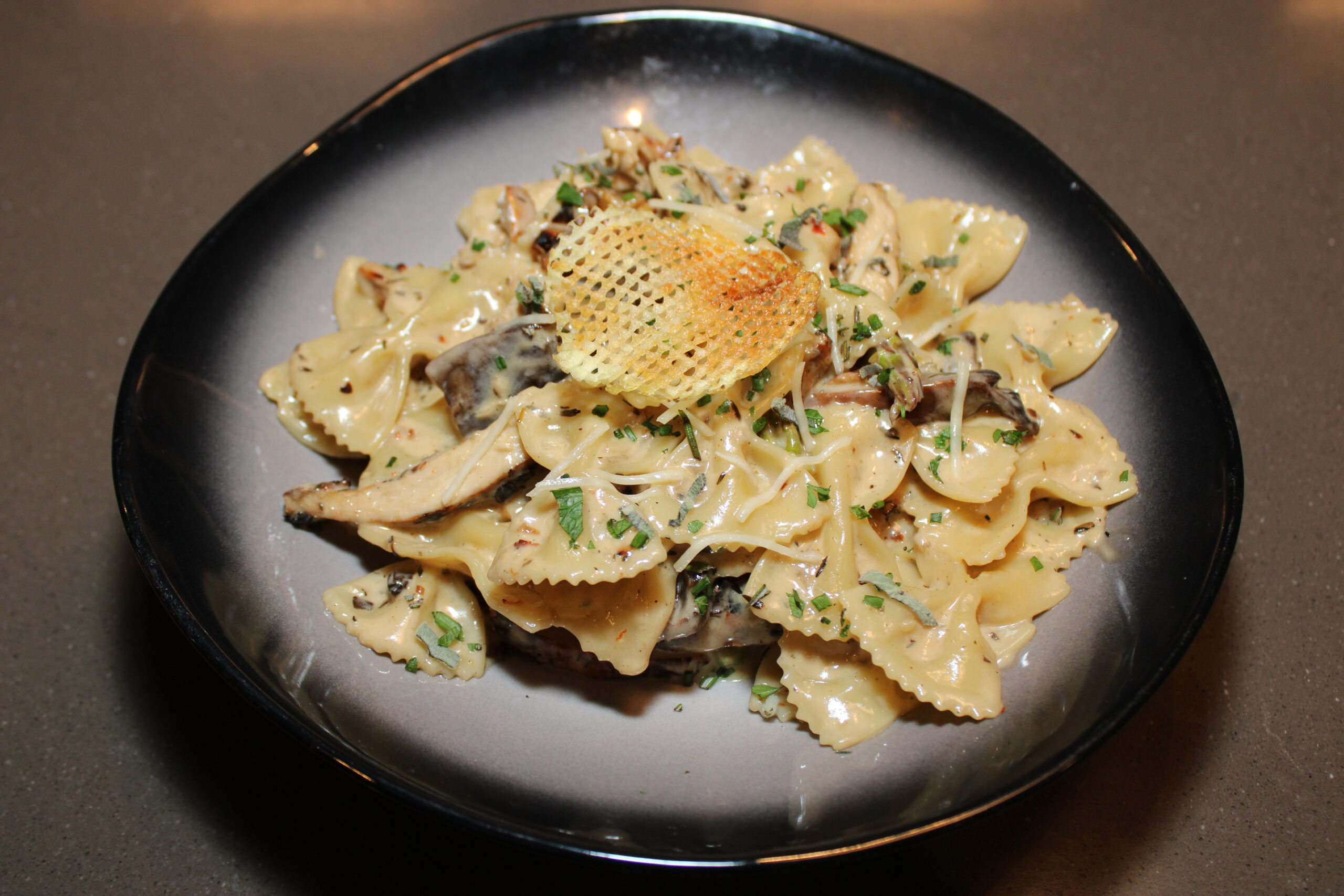 Image of Jerk Chicken Farfalle, a chicken pasta with creamy sauce, topped with a waffle chip.