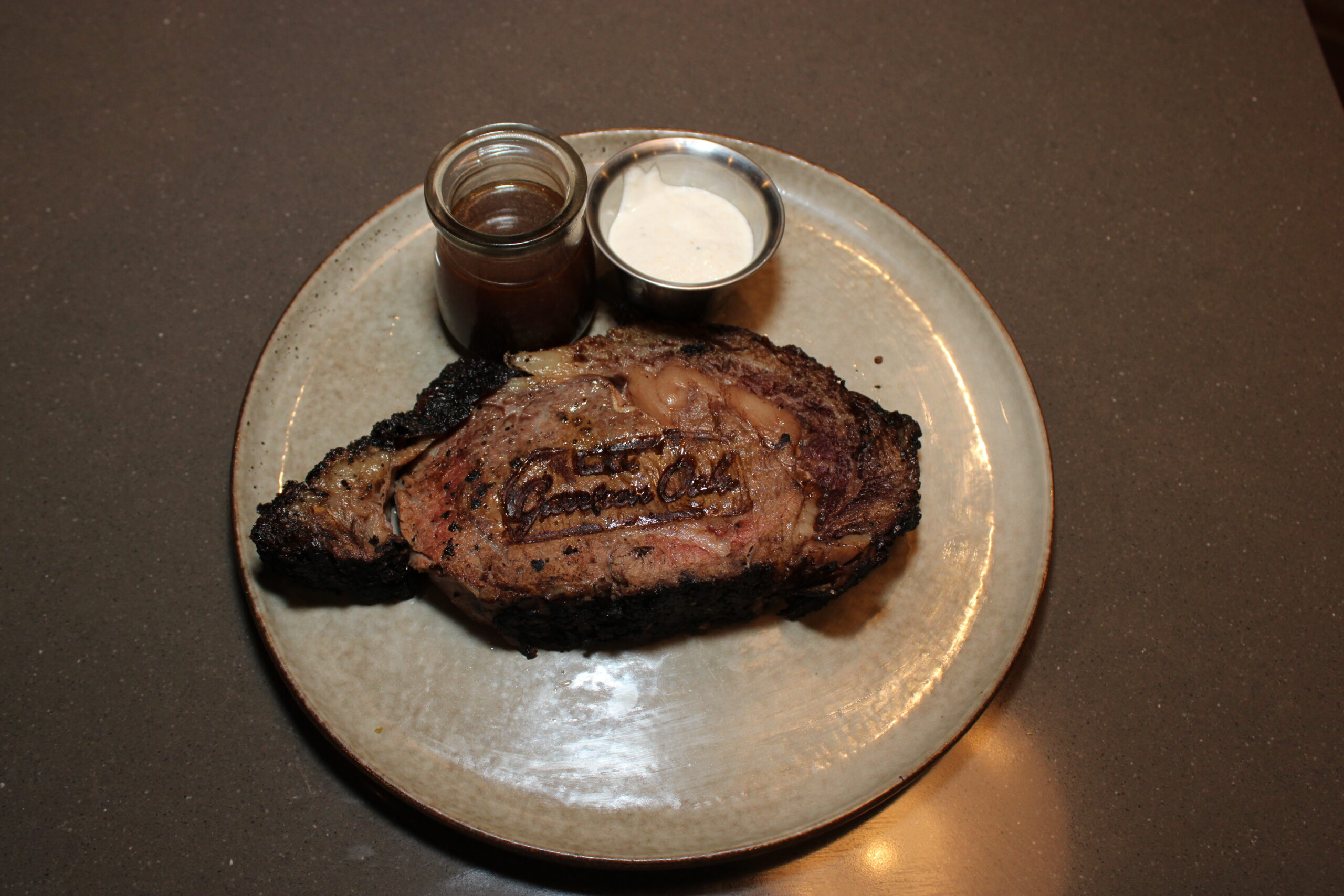 Image of Queen Cut Prime Rib with Au Jus and Horseradish Cream. The Prime Rib is branded with "Garrison Oak" wordmark